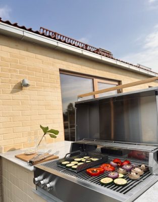Bluegaz Z Inbyggnadsgrill inbyggt i gult kakel med mat som grillas