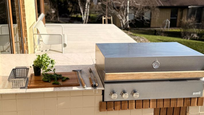 Bluegaz Z Inbyggnadsgrill inbyggd i ljustgult kaklat utekök med gul tegelvägg med uteplats i bakgrunden
